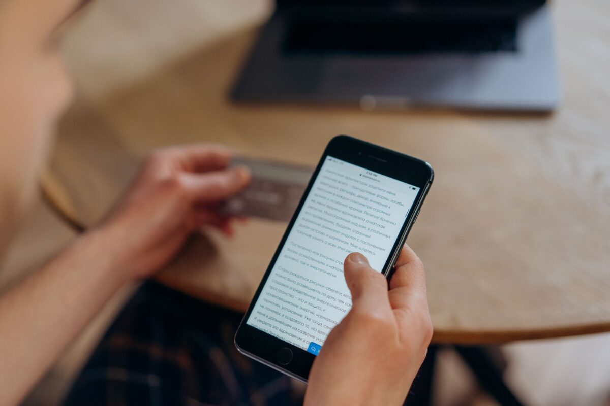 Gros plan sur une personne tenant un smartphone et une carte bancaire