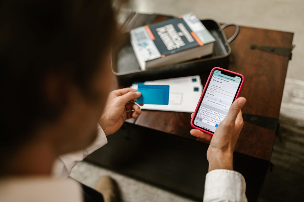 Personne réalisant un paiement en ligne avec un smartphone et une carte bancaire